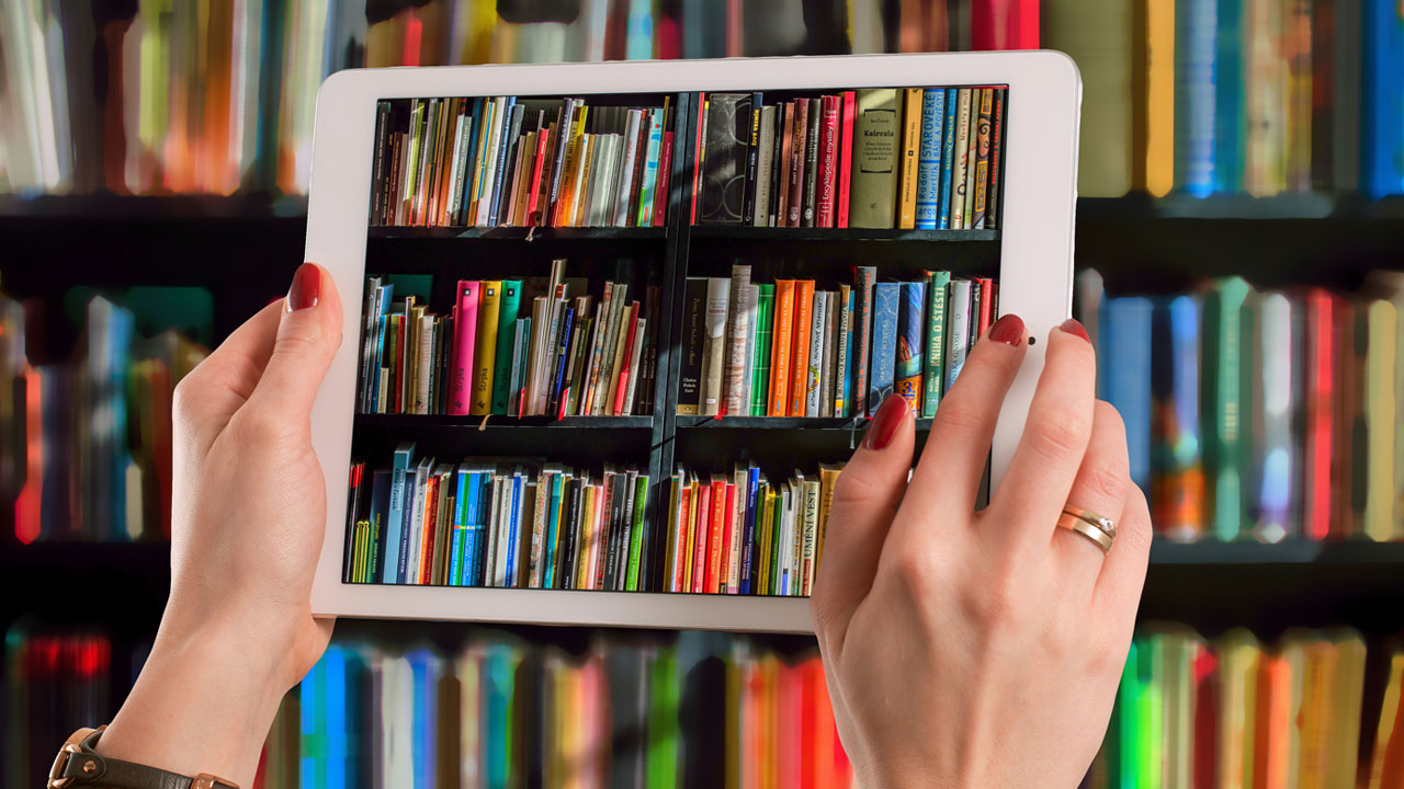 Bücherregal mit vielen Büchern. Im Vordergrund hält eine Frau ein Tablet hoch und macht vom Bücherregal ein Foto.